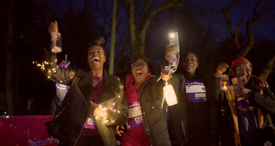 Four people taking part in the charity walk 'Walk of Light', holding up lanterns and wrapped in fairy lights.