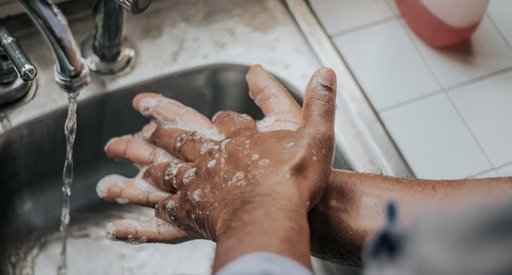 Someone washing their hands thoroughly under a tap.