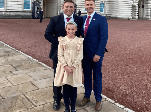 Will Findlay stands outside Buckingham Palace with Tom Youngs and his daughter