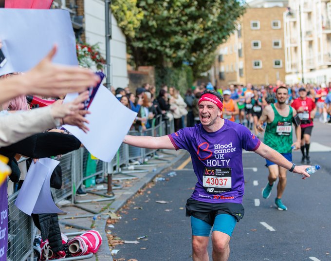 Blood Cancer UK male runner high fiving the cheer point at London Marathon 2022