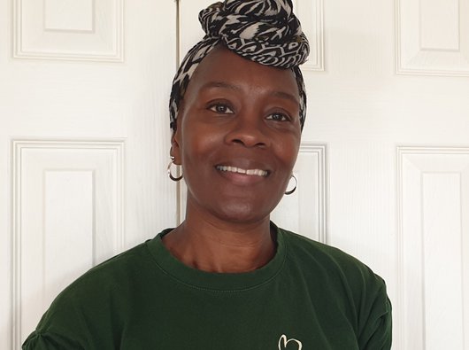 Photo of Yvonne, smiling and wearing a patterned head scarf.