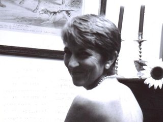 A black and white image of Calendar Girl Angela Knowles smiling over her shoulder with a sunflower in the background.