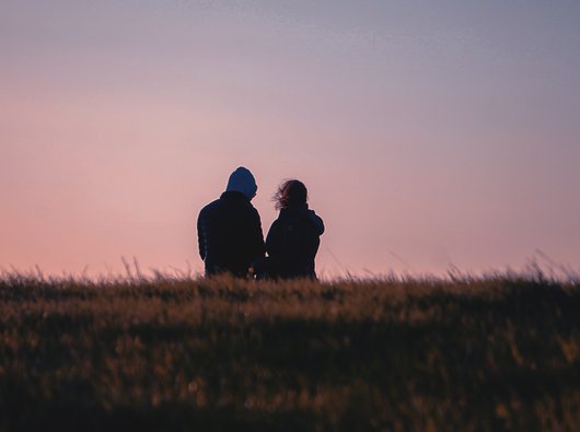 A couple out walking on a heath, seen from behind against the sky