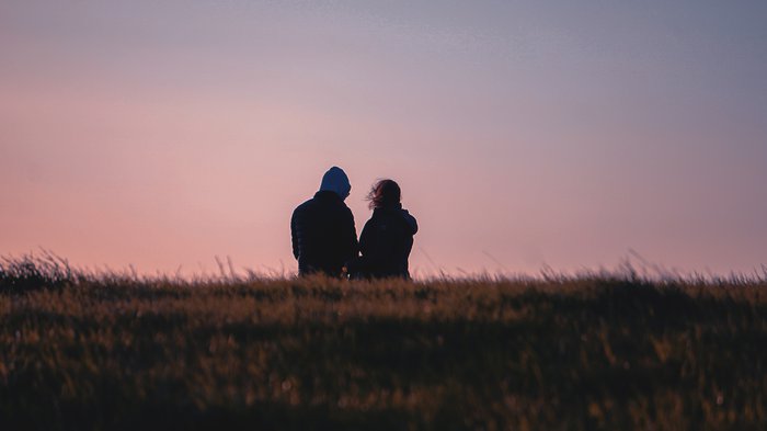 A couple out walking on a heath, seen from behind against the sky