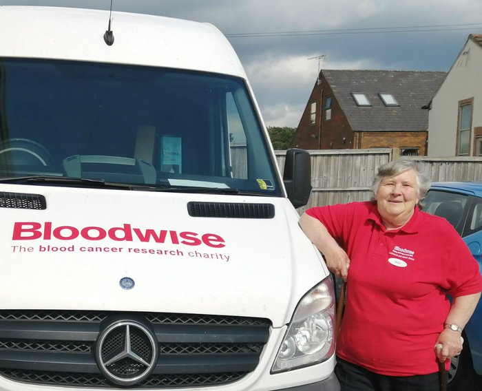 A Bloodwise van with its driver Chris posing alongside it.