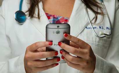 A doctor in a lab coat holding a mobile phone.