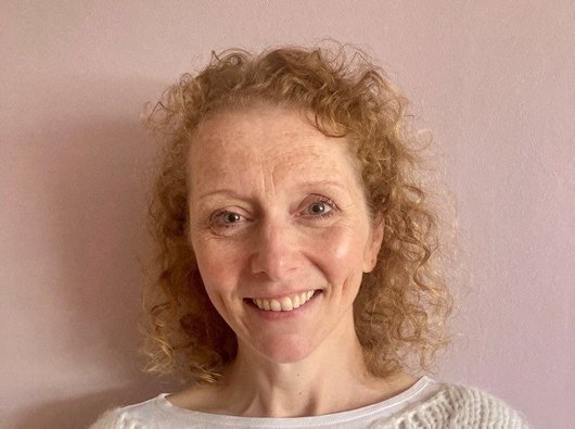 A photo of our Senior Support Services Nurse, Gemma. She is a smiling white woman with fair curly hair in a cream coloured top.