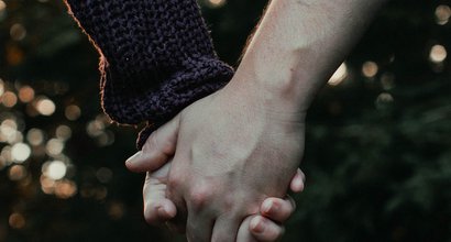 A couple hold hands - the image focuses on their hands.
