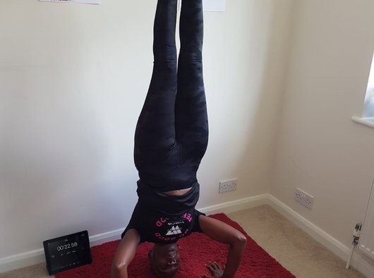 Yvonne, who was diagnosed with acute myeloid leukaemia (AML), standing on her head in her living room.