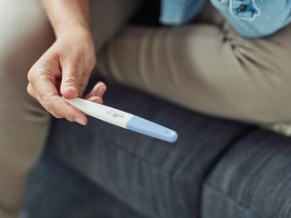 A hand holding a pregnancy test