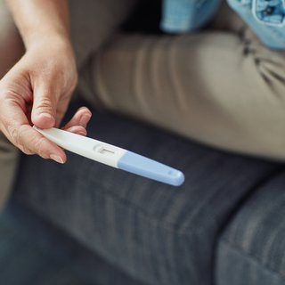 A hand holding a pregnancy test