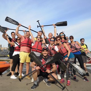 The itsu dragon boar team at the Dragon Boat race pose together with oars held aloft.