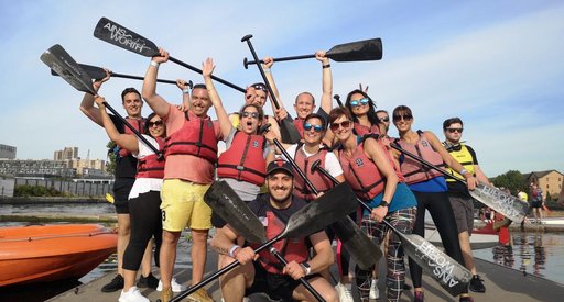 The itsu dragon boar team at the Dragon Boat race pose together with oars held aloft.