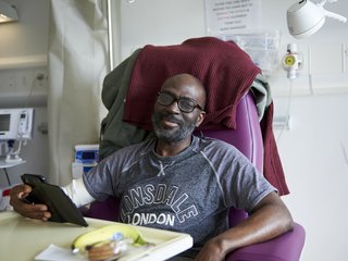 A man sitting in a chair in hospital, with medical equipment around him.