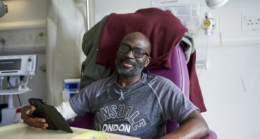 A man sitting in a chair in hospital, with medical equipment around him.