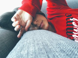 Woman lying on sofa looking tired.