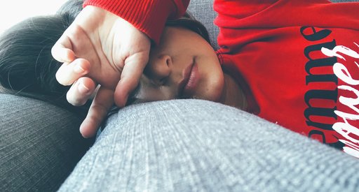 Woman lying on sofa looking tired.