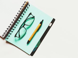 An open notebook with glasses and a pen on top of a page