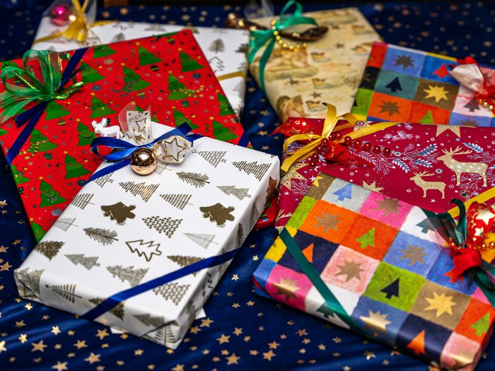 A selection of presents wrapped in Christmas paper with ribbons and gift tags