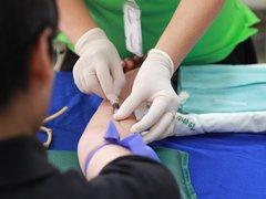 A close up of a person with a needle in their arm giving blood.