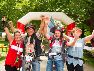 Bloodwise fundraisers in fancy dress as pirates, cheering at the finish line of a marathon