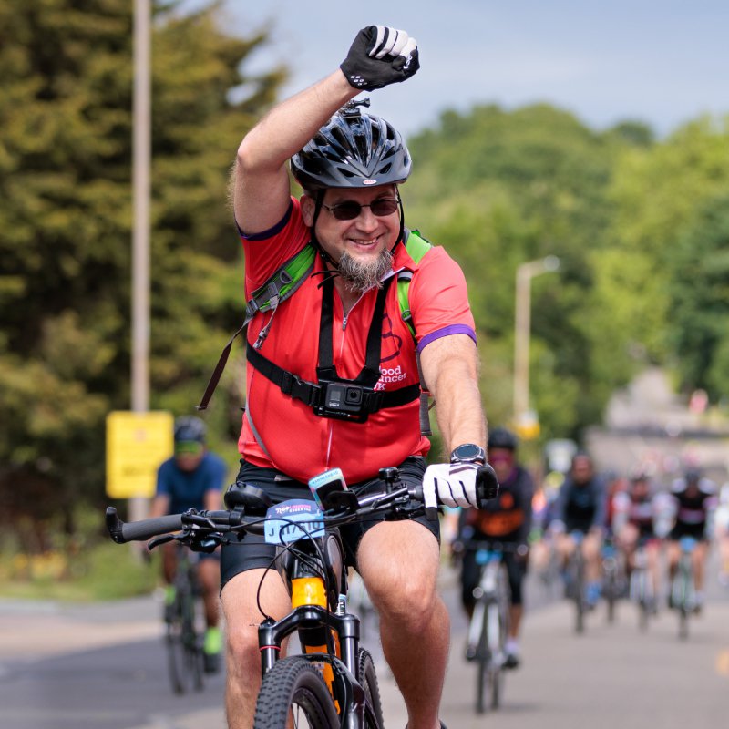 A man riding a bike smiles and punches the air during the 2022 Ride London event