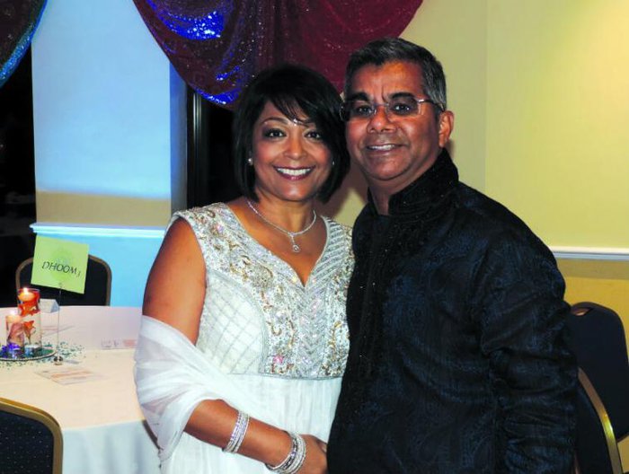 A middle aged couple pose for a photograph at a wedding.
