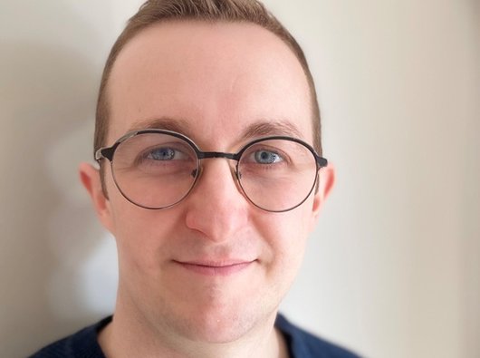 A photo of our Support Services Manager, Tom. The image shows a white man with glasses and fair hair in a blue top.