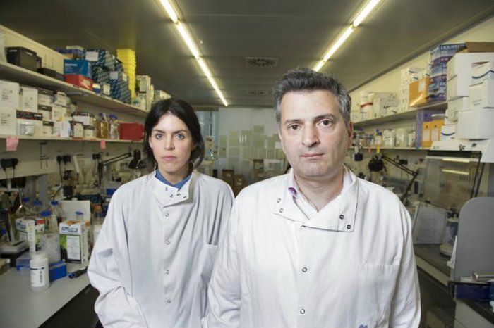 Two scientists pose together in a lab - one female, one male.