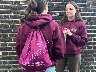 Two people facing each other wearing burgundy hoodies, made for the Walk of Light event