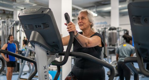 A woman exercising on a cross-trainer in a gym.